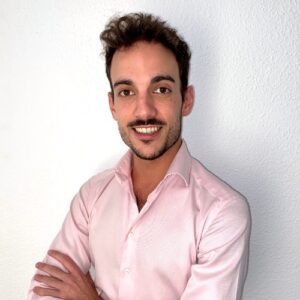 Psicólogo Juanfran, con camisa rosa y brazos cruzados, sonriendo a cámara.