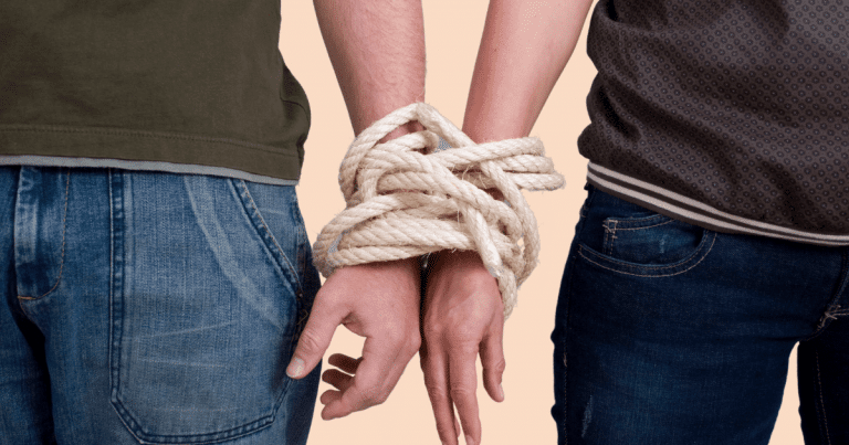 Primer plano de dos manos de chicos entrelazadas y atadas con una cuerda, sugiriendo una conexión fuerte pero también restrictiva.