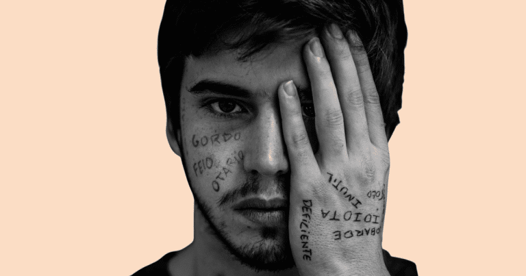 Un adolescente hombre tapándose un ojo, con su rostro pintado con diferentes insultos, simbolizando el impacto del acoso y la indefensión aprendida.