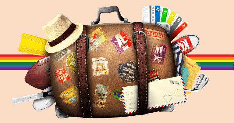 Una maleta de viaje con varios distintivos y pegatinas de destinos, y la bandera arcoíris LGTBIQ+ de fondo.