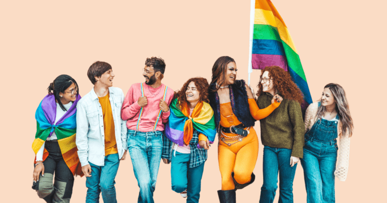 Siete personas diversas de la comunidad LGTBIQ+, con banderas y complementos de orgullo, apoyadas en un muro y sonriendo mientras se miran unas a otras.
