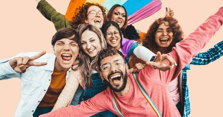 Un grupo de siete personas diversas (incluyendo diferentes géneros y etnias) muy contentas, con los brazos abiertos y mostrando varios símbolos LGTBIQ+ como banderas