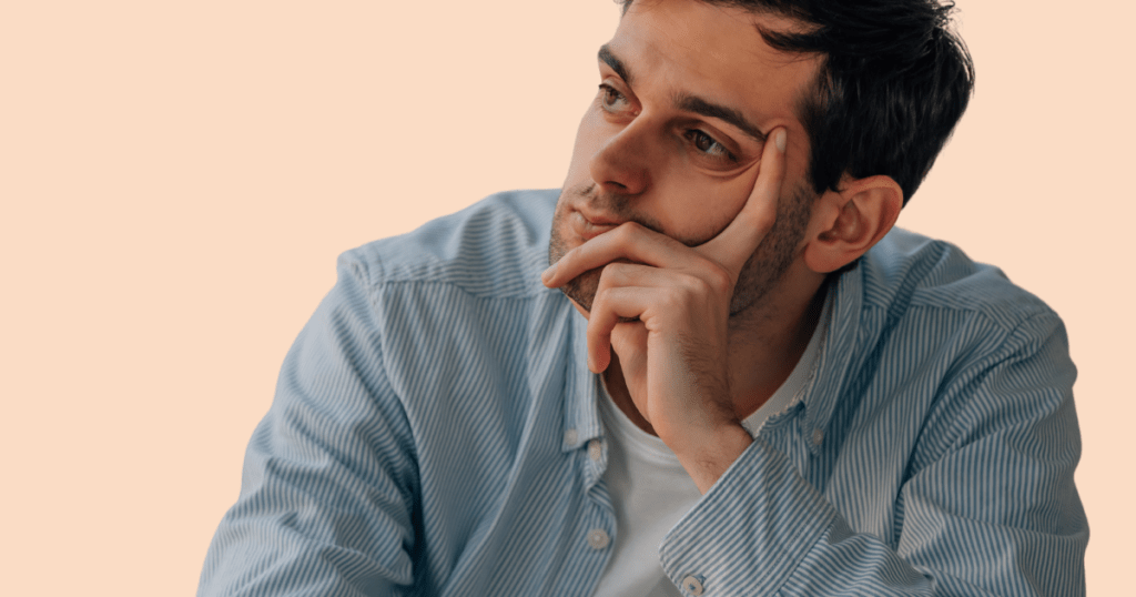 Un hombre con expresión pensativa, apoyando la mano en su cara, simbolizando preocupación o introspección.