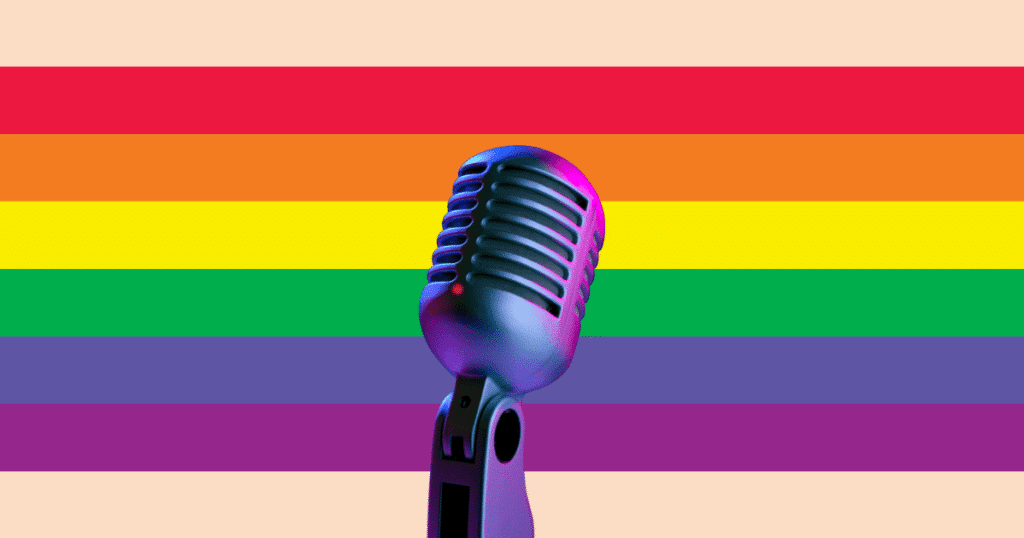 Un micrófono de escenario con la bandera arcoíris LGTBIQ+ difuminada de fondo, sugiriendo música y expresión.