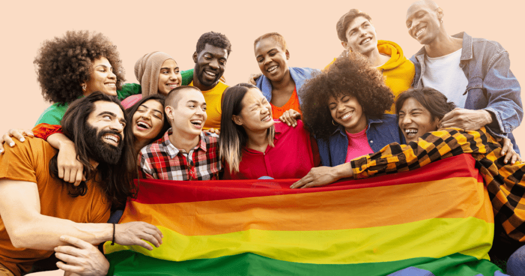 Un grupo diverso de personas sonriendo y sosteniendo una gran bandera arcoíris del Orgullo LGTBIQ+ en una manifestación.