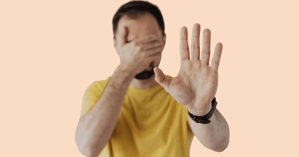 Un chico tapándose la cara con la palma de la mano, con una expresión que sugiere vergüenza, ocultamiento o evitación.