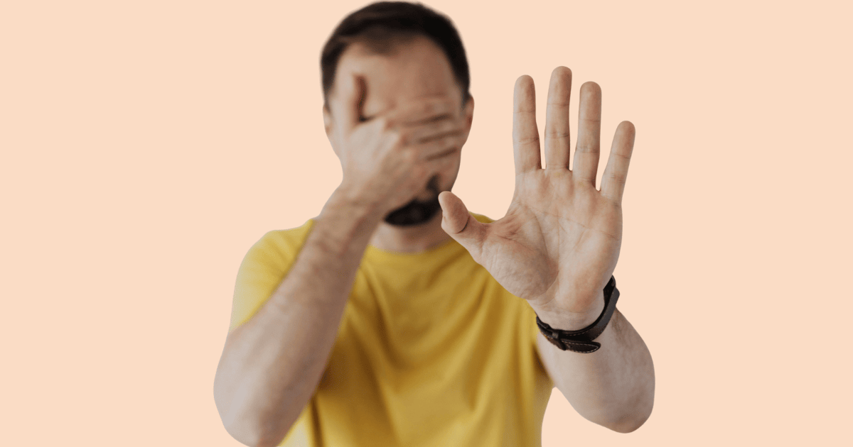 Un chico tapándose la cara con la palma de la mano, con una expresión que sugiere vergüenza, ocultamiento o evitación.