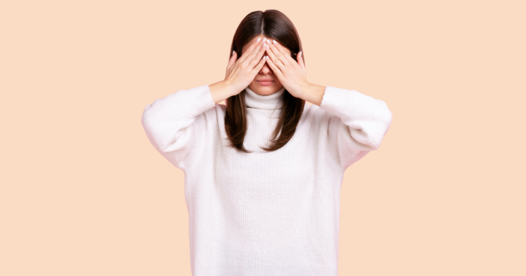 Una chica con las manos cubriendo sus ojos, en un gesto que simboliza la vergüenza, el ocultamiento o la incapacidad de verse a sí misma.