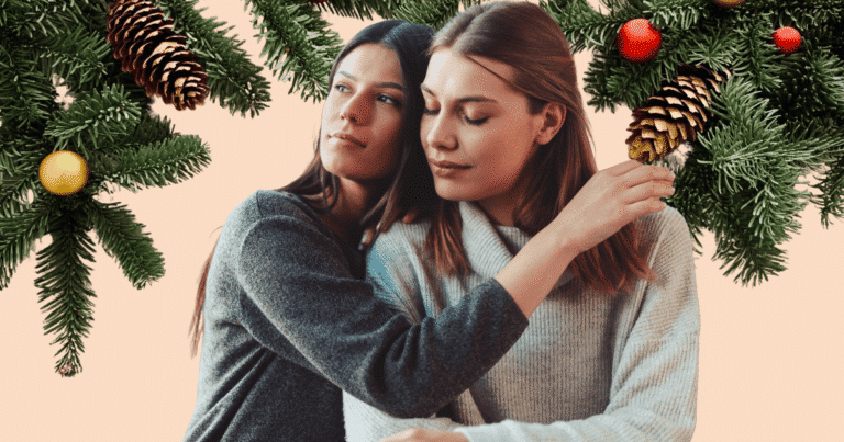Pareja de mujeres lesbianas abrazándose cariñosamente frente a un árbol de Navidad iluminado, simbolizando la unión y el afecto en el hogar.
