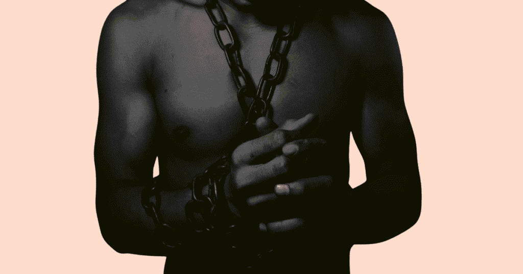 Plano cercano de un chico desnudo atado con cadenas, simbolizando el consentimiento y el juego de roles en el kinky.
